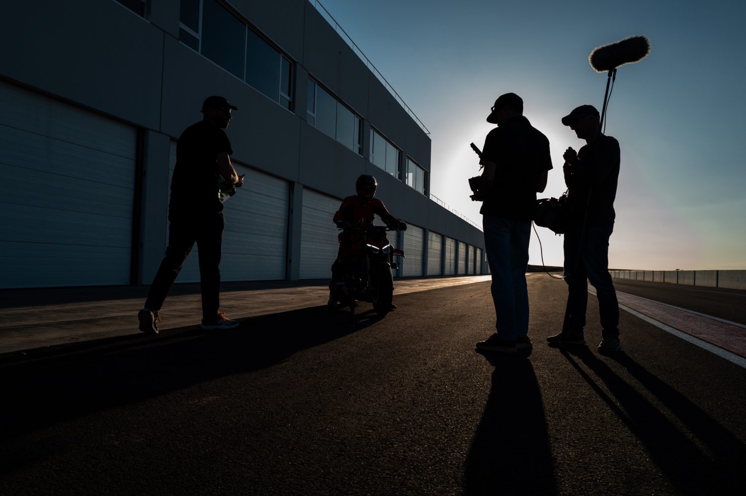 Crew and boom operator on a race circuit at sunset